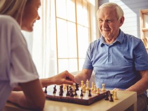 Volunteer Playing Chess With Senior